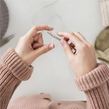 tutoriel Mains tenant aiguille à tricoter et du fil.