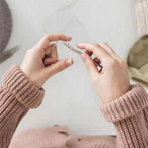 tutoriel Mains tenant aiguille à tricoter et du fil.